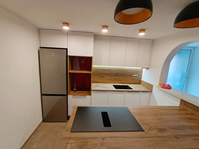 Cocina blanca con nicho decorativo en rojo junto a la nevera