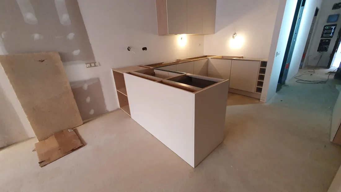 Cocina en U con isla blanca recién instalada por Montajes Aguilar