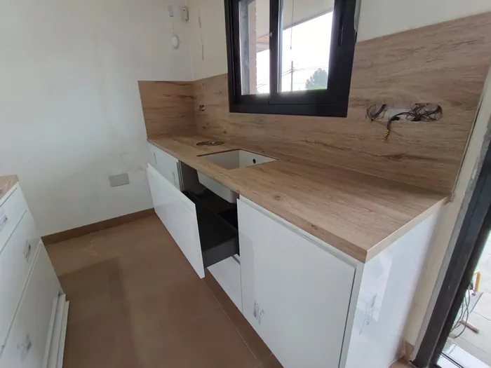 Rincón de cocina en montaje con encimera de madera junto a ventana